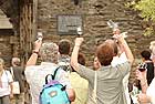 Gut gelaunte Gste winken bei der Rotweinprobe und dem Rotweinfest vom er Markplatz Spaziergngern auf der mittelalterlichen Stadtmauer zu.